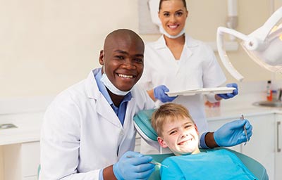 A dentist with his dental assistand and young patient